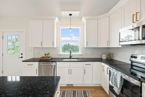 a kitchen with stainless steel appliances granite countertop a refrigerator a stove a sink a dining table and chairs with wooden floor