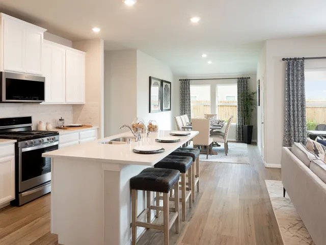a kitchen with stainless steel appliances a stove a sink cabinets and a refrigerator