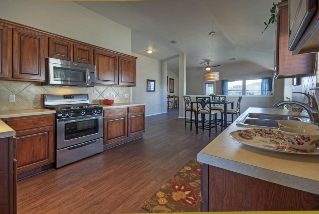 a kitchen with stainless steel appliances wooden floors stove and cabinets