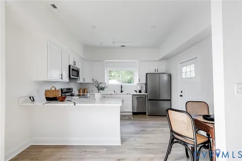 a kitchen with stainless steel appliances a refrigerator a stove a sink cabinets and a dining table