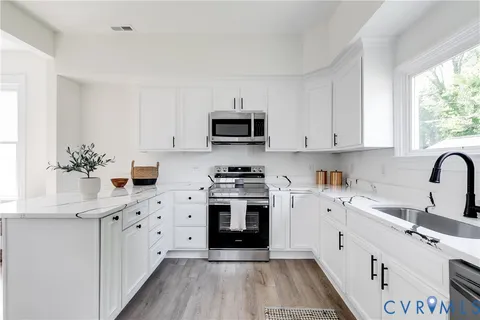 a kitchen with stainless steel appliances white cabinets a sink and a stove