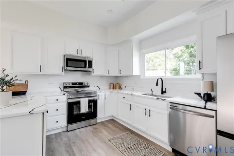 a kitchen with cabinets appliances a sink and a window