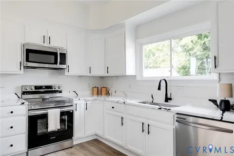 a kitchen with cabinets stainless steel appliances a sink and a window
