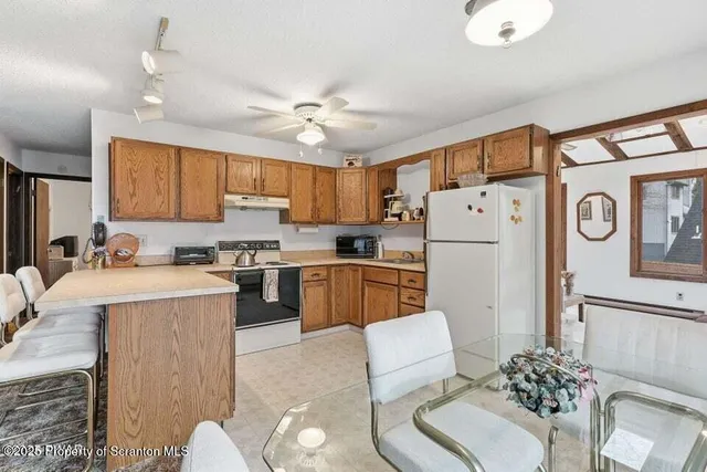 a kitchen with stainless steel appliances granite countertop a refrigerator a sink a stove a dining table and chairs with wooden floor