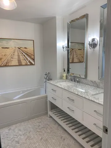 a bathroom with a granite countertop sink mirror and bathtub