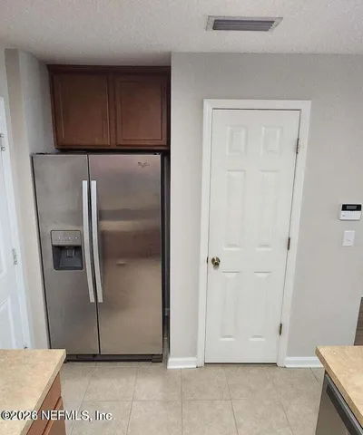 a view of a refrigerator in kitchen and white cabinets