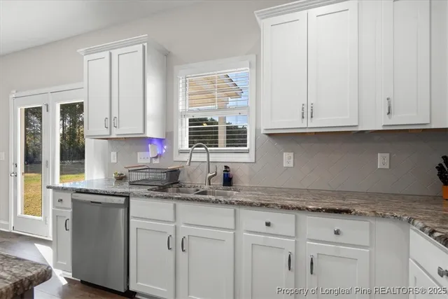 a kitchen with granite countertop white cabinets and a sink