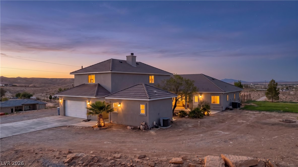 575 Gann Avenue Logandale, NV 89021 - Photo 1 of 75 Perched on a hill, this desert home offers illuminated facades against a dramatic twilight sky.