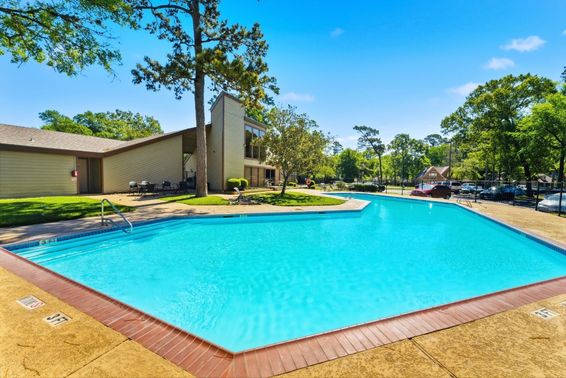 12900 Walden Road, Unit 219B Montgomery, TX 77356 - Photo 20 of 41 a view of a swimming pool with lawn chairs under an umbrella
