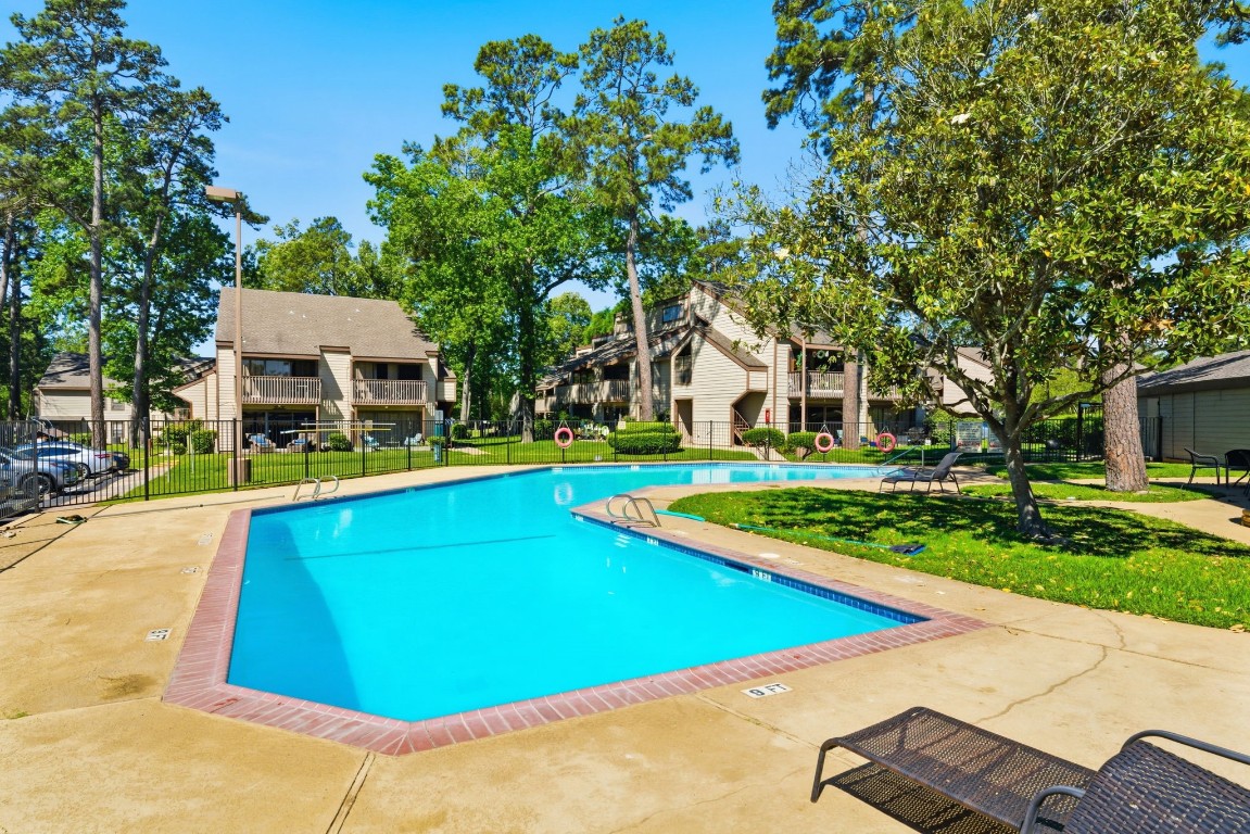 12900 Walden Road, Unit 219B Montgomery, TX 77356 - Photo 22 of 41 a view of a swimming pool with lawn chairs under an umbrella