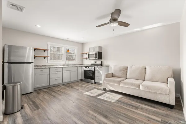 a living room with stainless steel appliances furniture and a kitchen view