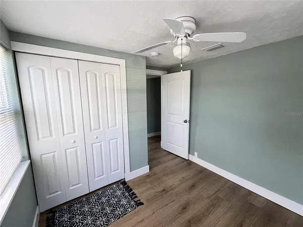 an empty room with wooden floor closet and windows