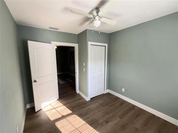 an empty room with wooden floor and fan