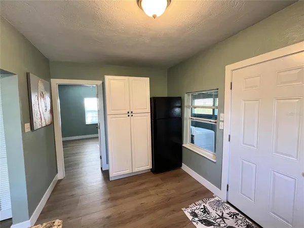 a view of a kitchen with refrigerator and wooden floor