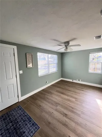 an empty room with wooden floor cabinet and windows
