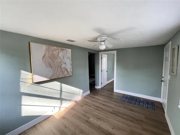 a view of an empty room with wooden floor and a window