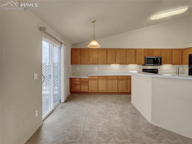 8599 Tibbs Road Peyton, CO 80831 - Photo 15 of 38 Terrific eat-in kitchen complete with breakfast bar, built in desks, updated appliances and walk-out to the deck!