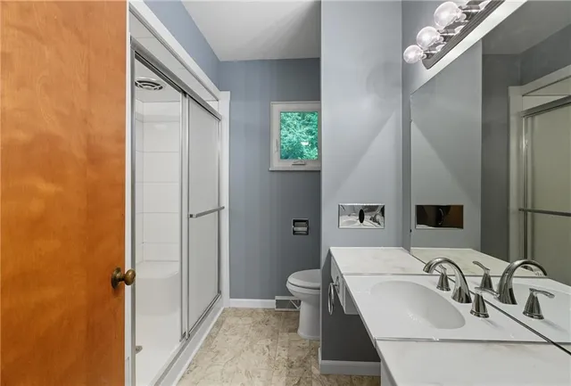 a bathroom with a sink a toilet and shower a mirror