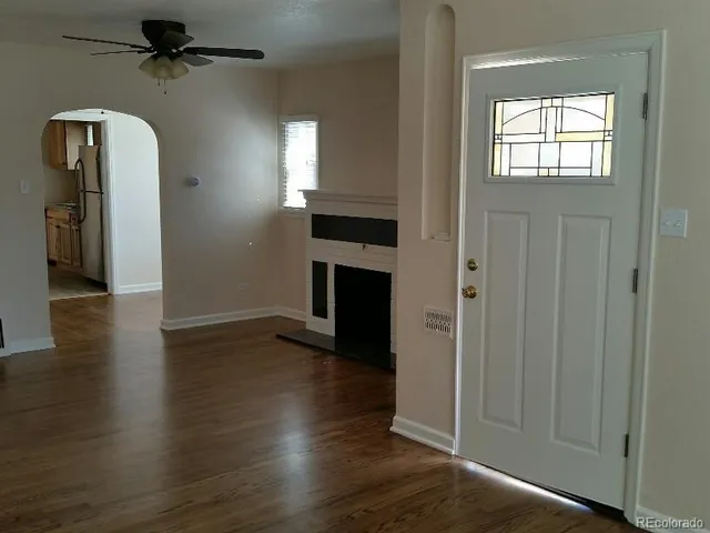 an empty room with wooden floor a fireplace and windows