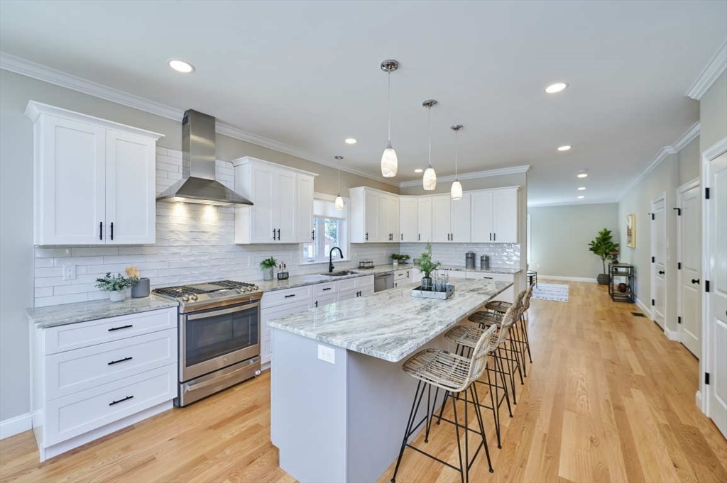 60 Peach Orchard Road Burlington, MA 01803 - Photo 13 of 42 a kitchen with stainless steel appliances kitchen island granite countertop a stove a sink a refrigerator and white cabinets with wooden floor