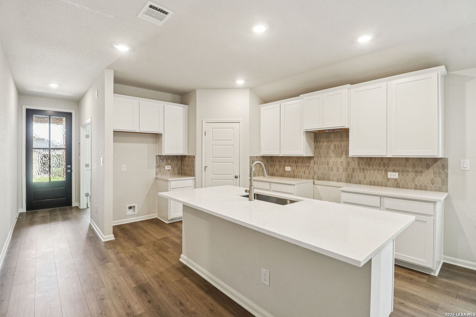 9909 Paladin Ridge San Antonio, TX 78254 - Photo 13 of 41 a kitchen with a sink a stove a refrigerator and white cabinets with wooden floor