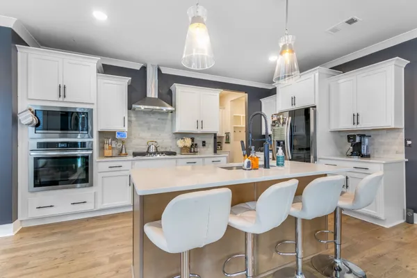 a large kitchen with stainless steel appliances granite countertop a lot of counter space and wooden floor