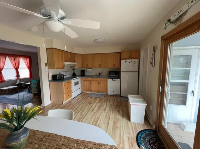 a kitchen with a refrigerator a sink dishwasher a dining table and chairs with wooden floor