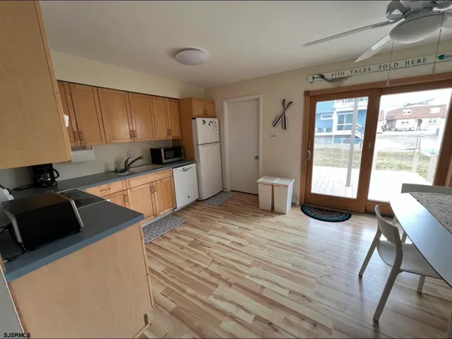 a kitchen with a stove a refrigerator a sink a dining table and chairs with wooden floor