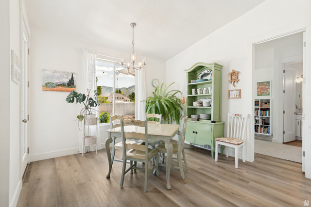 683 Kings Landing Tooele, UT 84074 - Photo 7 of 39 Bright dining area featuring wood-finish flooring, a contemporary chandelier, and a large window