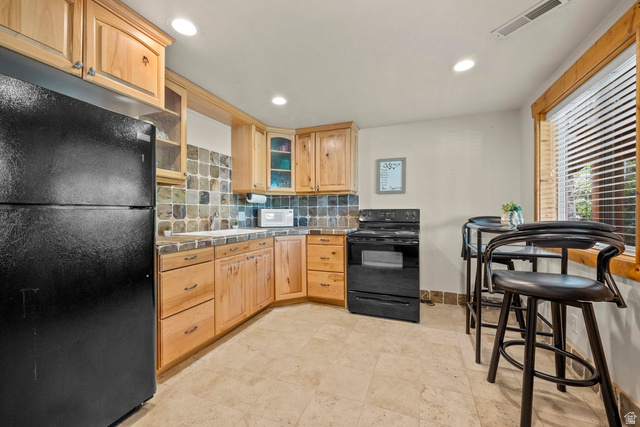 288 South Hillside Drive Elk Ridge, UT 84651 - Photo 16 of 27 Kitchen with black appliances, glass fronted cabinets, light wood finish cabinetry, and recessed lighting