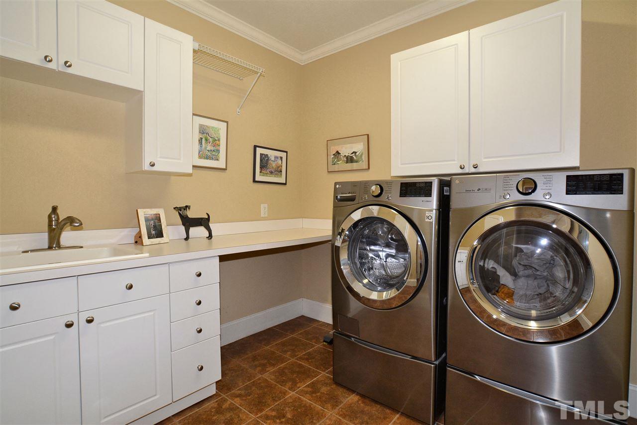 1089 Tacketts Pond Drive Raleigh, NC 27614 - Photo 19 of 30 Laundry Room has Tile Flooring, Folding Area, Laundry Sink, Cabinets & Flip down Ironing Board.