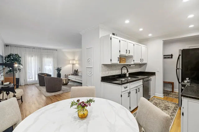 a kitchen with stainless steel appliances a stove a sink a dining table and chairs