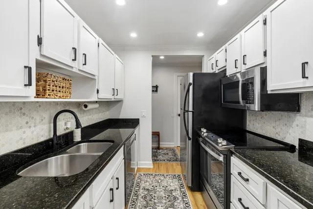 a kitchen with kitchen island granite countertop a sink stainless steel appliances and cabinets