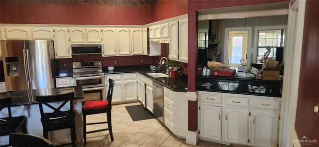 a kitchen with stainless steel appliances a stove a sink and white cabinets