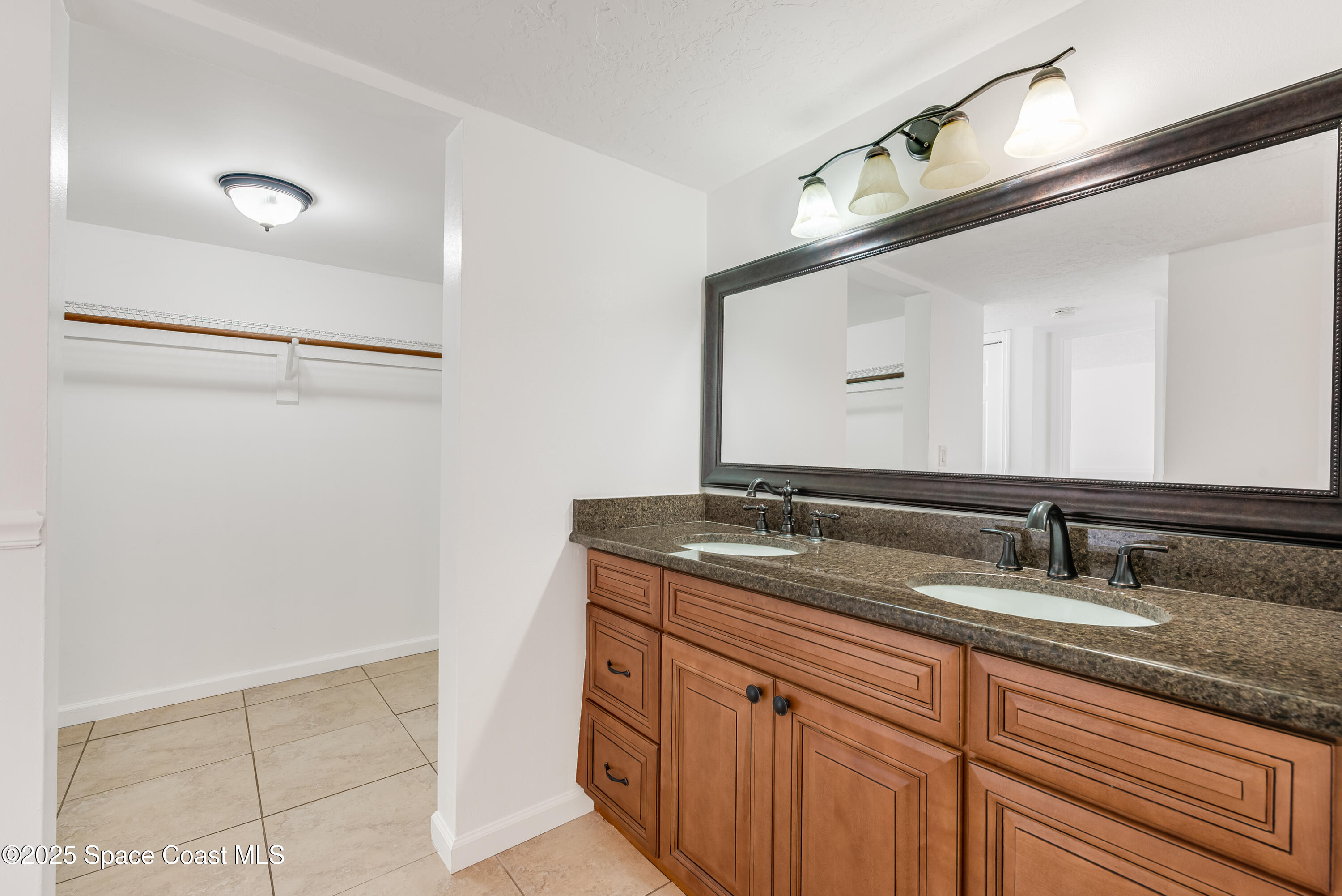 315 Tangle Run Boulevard, Unit 1023 Melbourne, FL 32940 - Photo 13 of 17 a bathroom with a granite countertop sink and a mirror