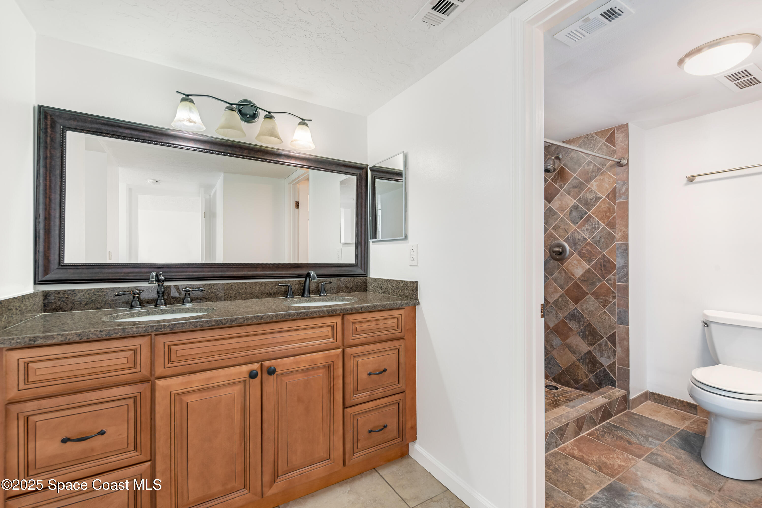 315 Tangle Run Boulevard, Unit 1023 Melbourne, FL 32940 - Photo 14 of 17 a bathroom with a granite countertop sink a toilet and a mirror