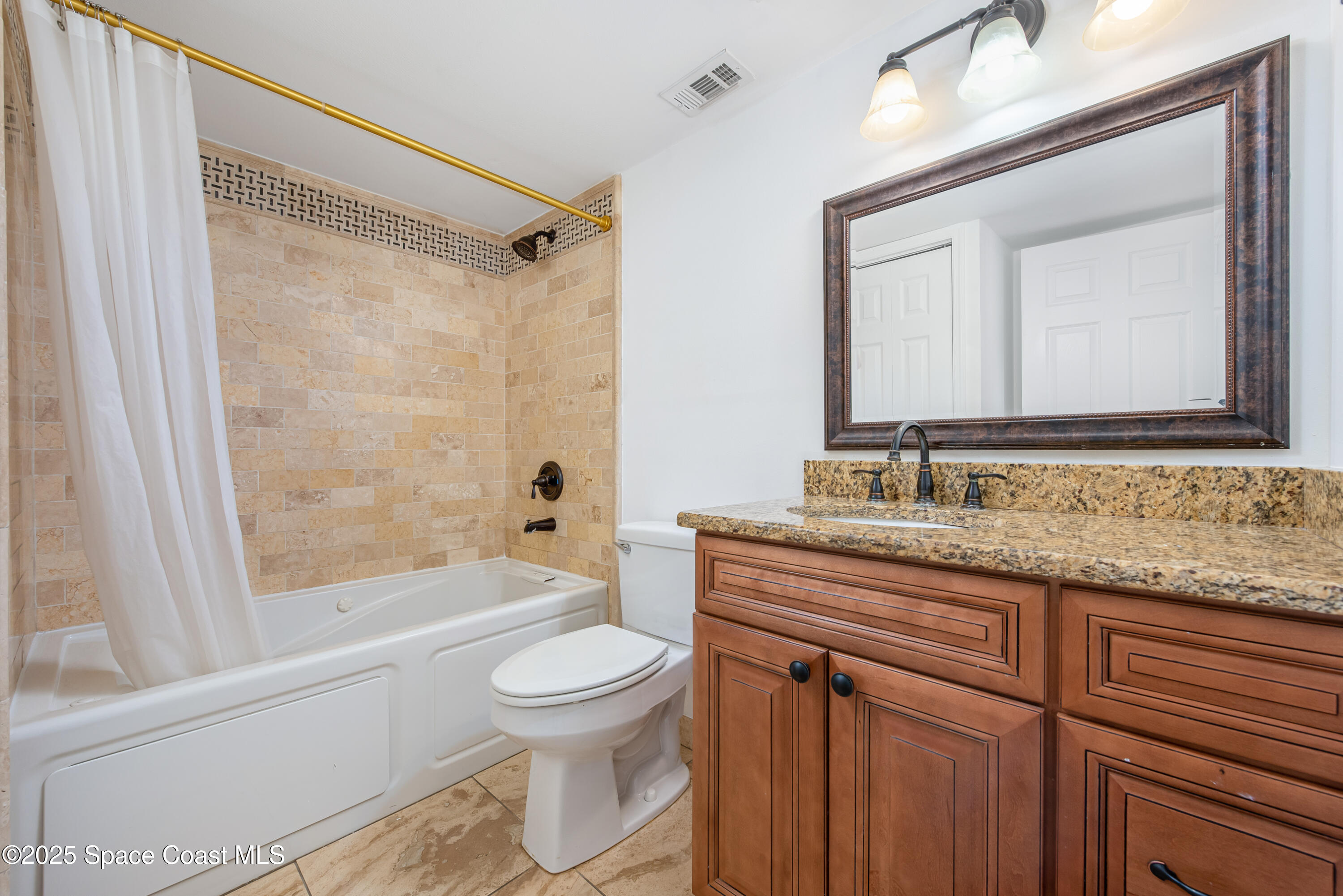 315 Tangle Run Boulevard, Unit 1023 Melbourne, FL 32940 - Photo 17 of 17 a bathroom with a granite countertop sink toilet a mirror and a shower