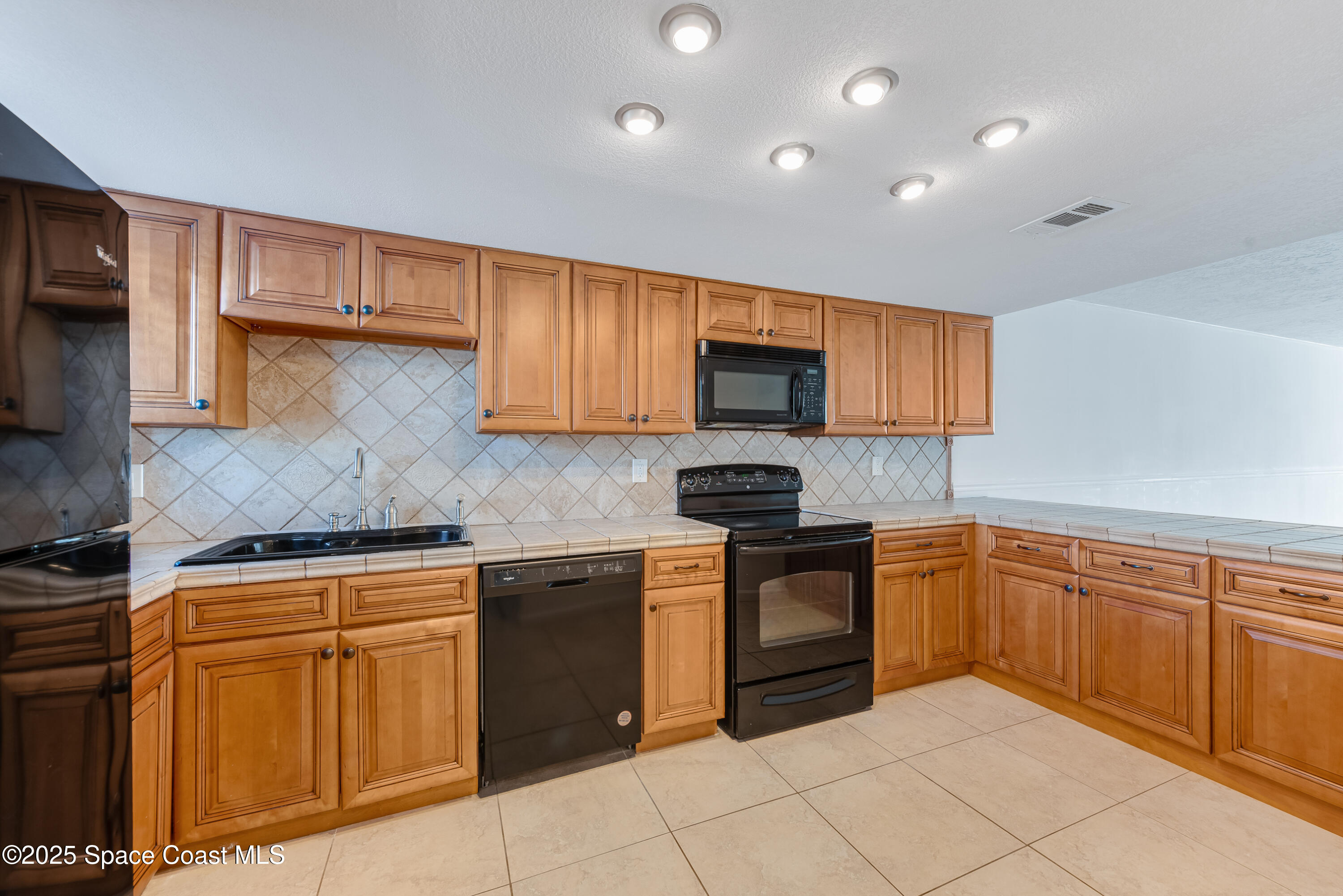 315 Tangle Run Boulevard, Unit 1023 Melbourne, FL 32940 - Photo 9 of 17 a kitchen with stainless steel appliances granite countertop a stove top oven a sink dishwasher and a microwave oven on the blue kitchen countertops
