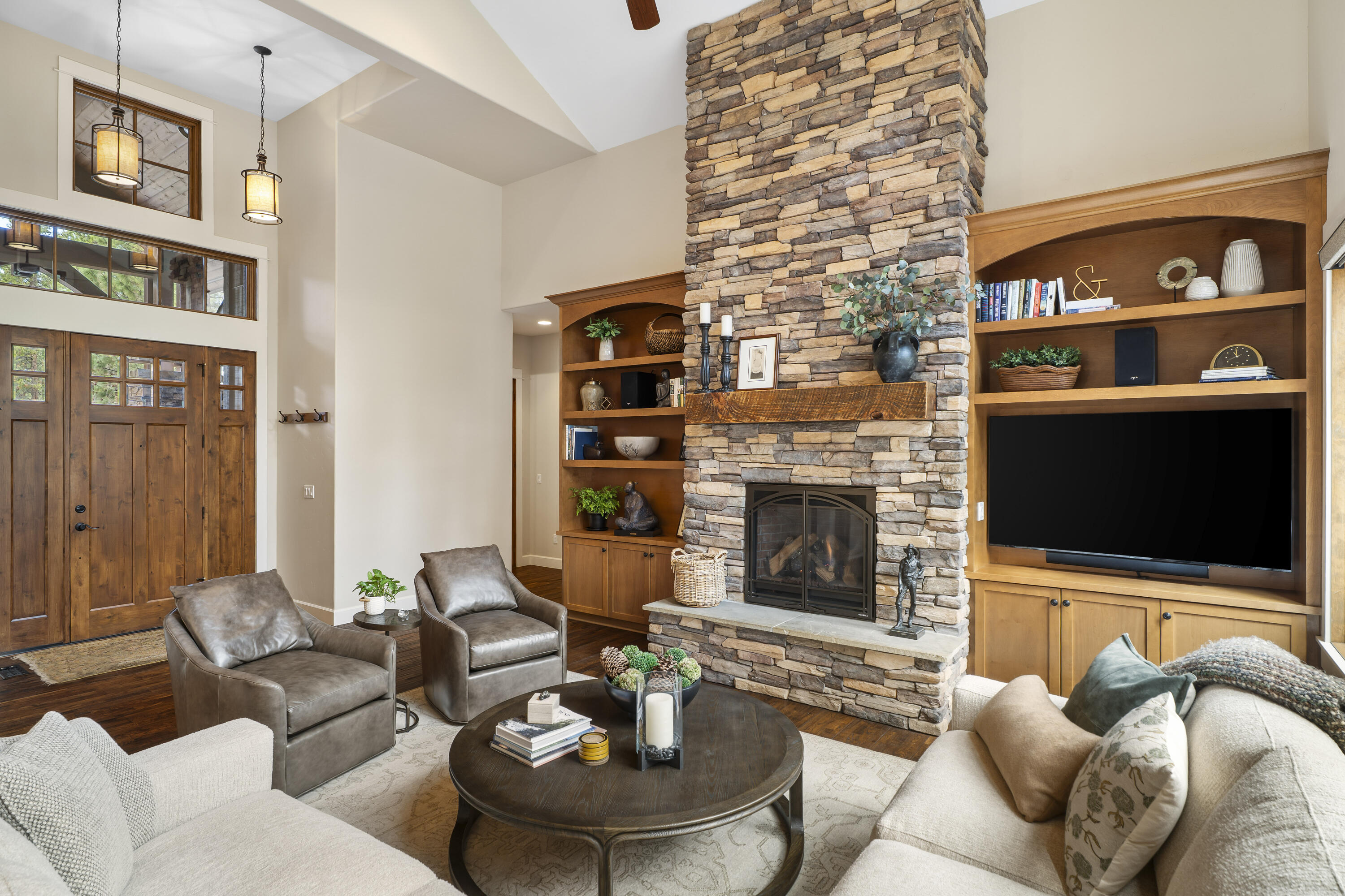 56155 Sable Rock Loop, Unit 277 Bend, OR 97707 - Photo 7 of 63 The inviting great room features soaring ceilings, rich hardwood floors, custom built-ins, and a striking floor-to-ceiling stone fireplace.