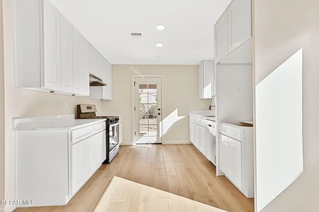 a kitchen with stainless steel appliances white cabinets and a stove top oven