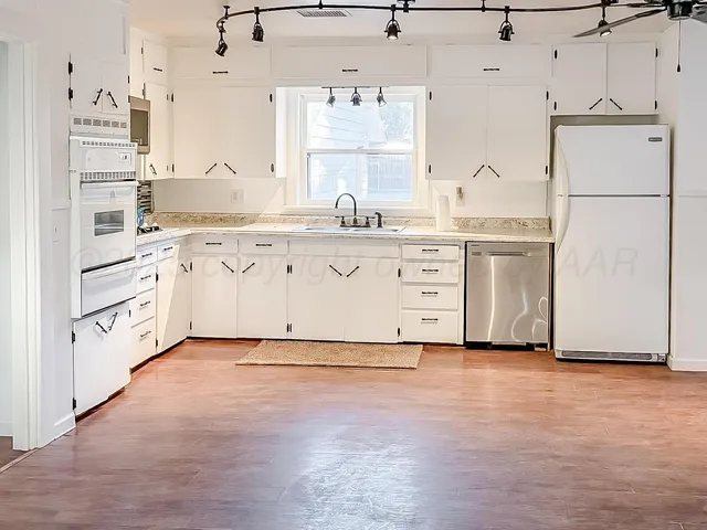 a kitchen with granite countertop a sink stainless steel appliances and cabinets