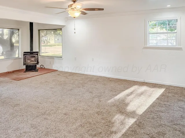 an empty room with windows and fan