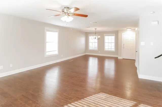 a view of an empty room with a window and wooden floor