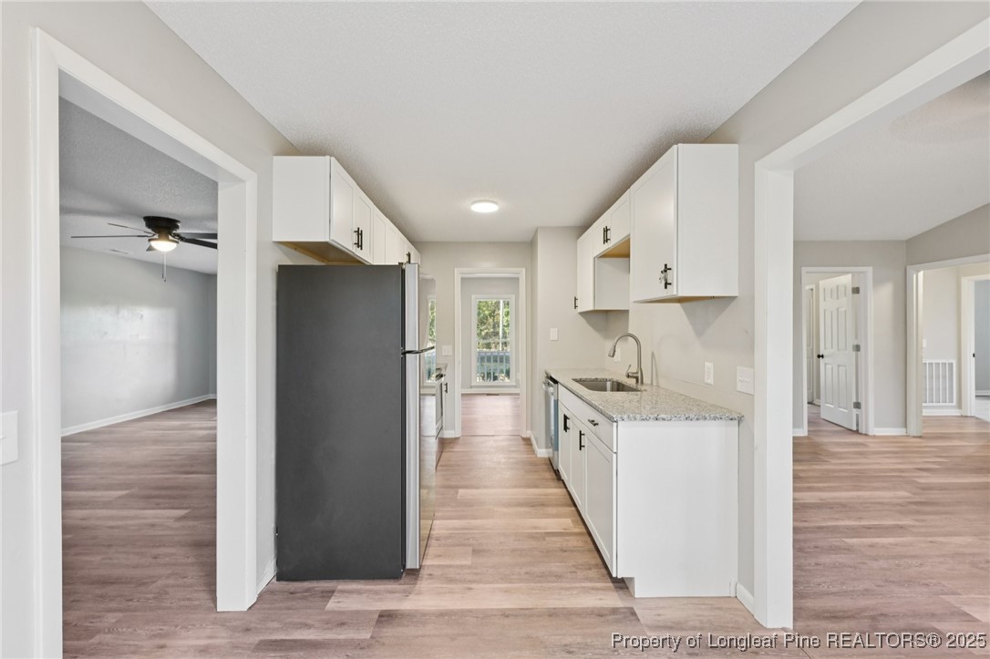 211 Lemuel Black Road Bunnlevel, NC 28323 - Photo 10 of 29 a kitchen with white cabinets and wooden floor