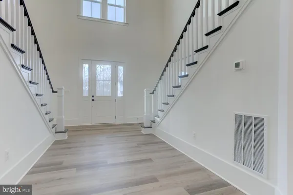 an empty room with wooden floor chandelier and windows