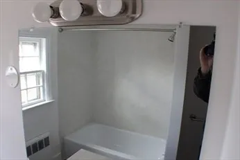 a bathroom with a bathtub a window and a shower