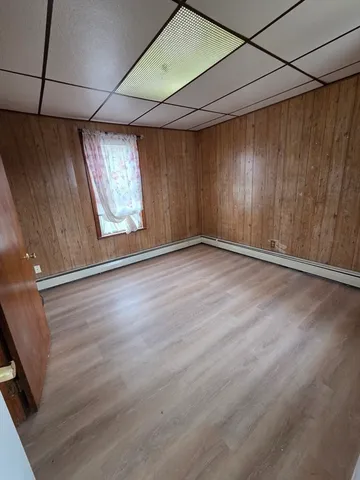 a view of an empty room with a window and wooden floor