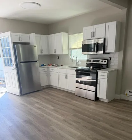 a kitchen with stainless steel appliances a refrigerator stove and white cabinets