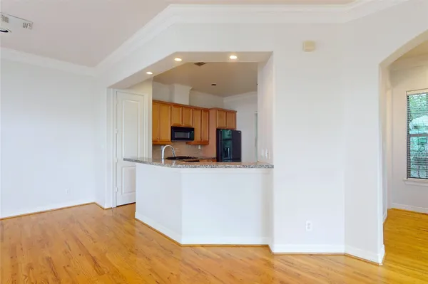 a view of kitchen and empty room with wooden floor