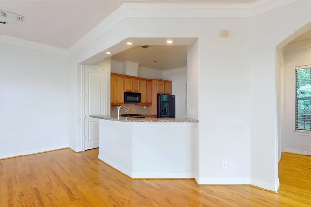 a view of kitchen and empty room with wooden floor